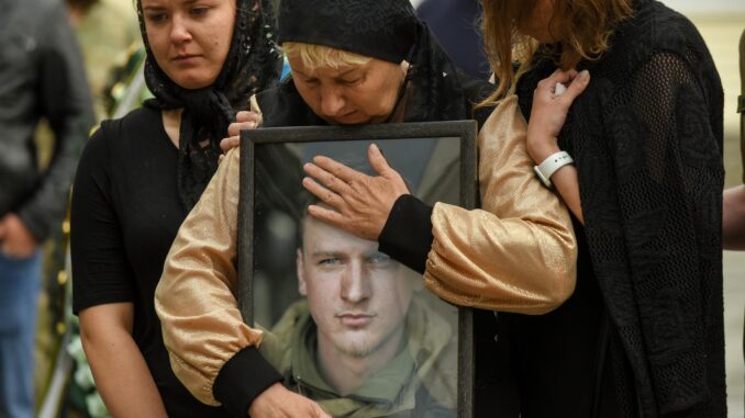 La madre de un soldado ucraniano abraza el retrato de su hijo durante su ceremonia fúnebre, en una imagen de archivo. EFE/ Oleg Petrasyuk
