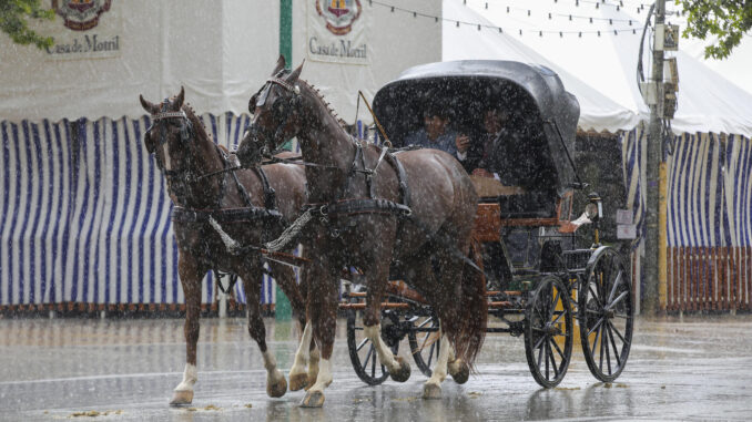 Un coche de caballos entre las casetas del recinto ferial de Almanjayar de Granada donde se celebra la Feria, durante la tormenta registrada este domingo. EFE/ Pepe Torres
