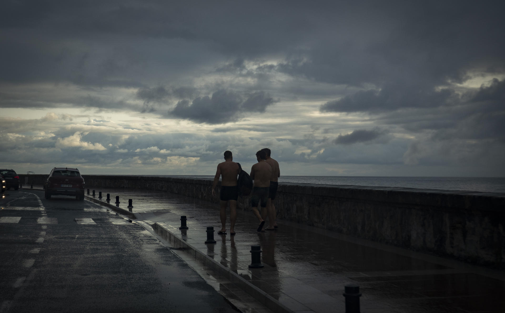 Varios hombres caminan bajo la lluvia a primera hora de este viernes en San Sebastián. EFE/Javier Etxezarreta
