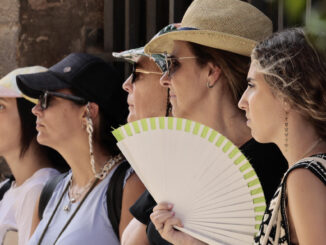 Varias personas se protegen del calor con gorras y abanico en Valencia hoy. EFE/Ana Escobar