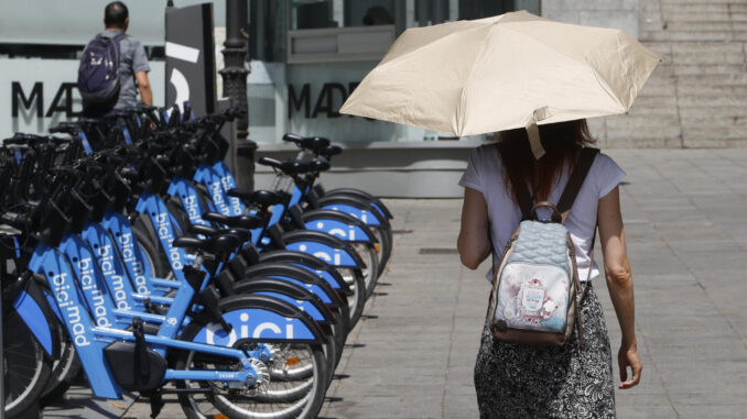 Una viandante se protege del sol con un paraguas mientras camina por el centro de Madrid donde este martes se alcanzarán los 39 grados centígrados. EFE/ Mariscal
