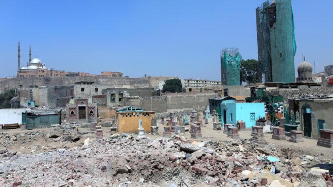 La Ciudad de los Muertos, la necrópolis medieval que forma parte de El Cairo histórico, está actualmente amenazada por el Gobierno de Egipto, que el pasado mes de mayo comenzó a demoler sus históricos mausoleos para dar paso a una nueva autopista, haciendo caso omiso a las advertencias de la Unesco y a su estatus como patrimonio de la Humanidad.
Las lápidas con inscripciones en árabe que sobresalen de entre las ruinas son el testigo de esta medida que busca unir el centro de El Cairo con la Nueva Capital Administrativa, una megalópolis en el desierto a unos 50 kilómetros al este de la ciudad, cuyo trazado atraviesa este camposanto con tumbas de más de 1.300 años donde yacen personajes ilustres de la historia, cultura y artes del país.
"Los cementerios se convirtieron en un museo que vinculaba este mundo y el más allá, y reunió los restos de aquellos que escribieron la historia de Egipto", publicó el investigador urbano egipcio Ibrahim Ezzeldin en la web The Tahrir Institute For Middle East Policy (TIMEP) a inicios de agosto. 
Este urbanista alertó de la pérdida que supone demoler este espacio donde descansan personalidades como Taqi al Din al Maqrizi, historiador cairota, cuya tumba ya fue demolida y retirada; mientras todavía resiste el sepulcro del escritor Taha Hussein, el "decano de las letras árabes", entre otros.
EFE/EPA/KHALED ELFIQI
