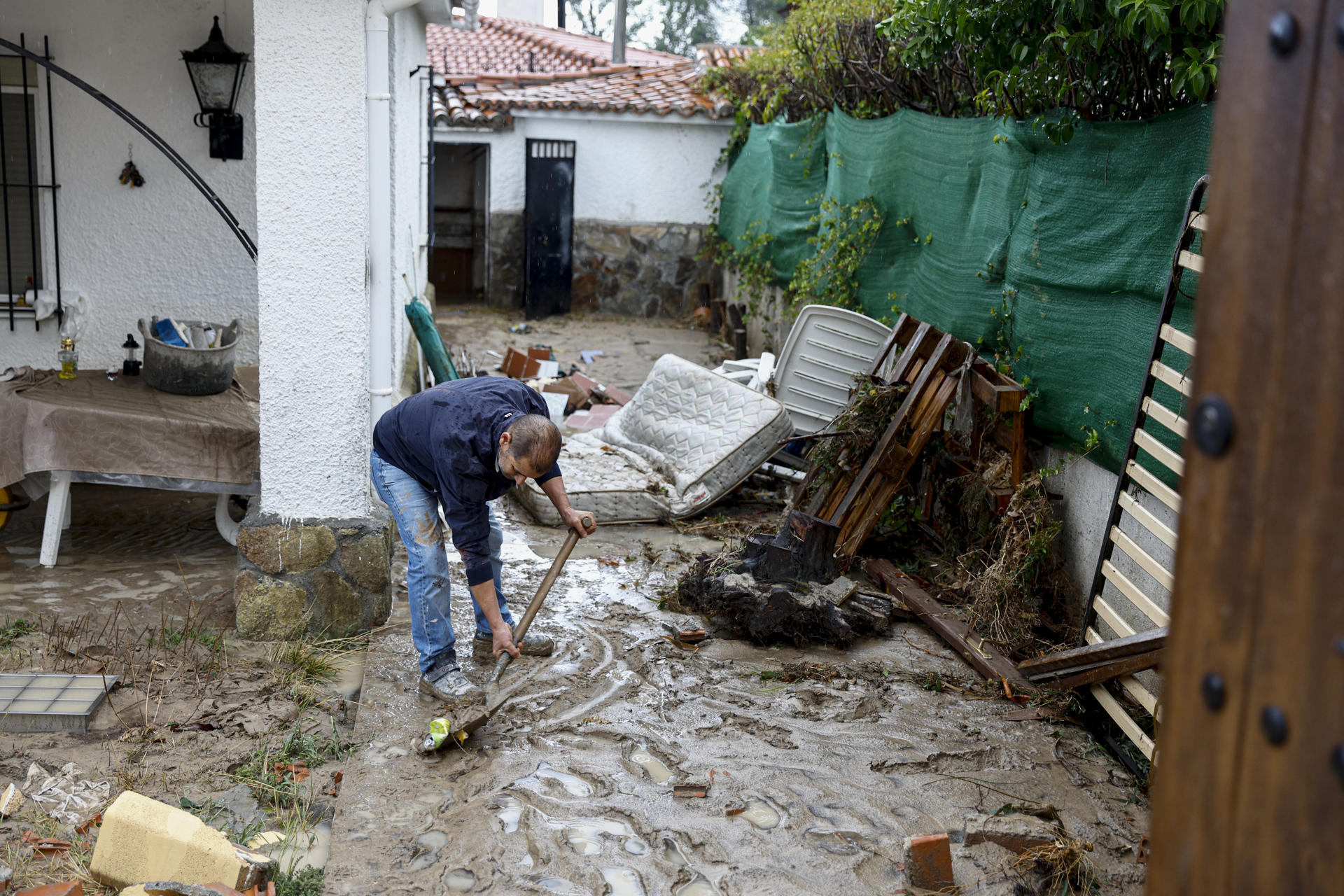 Un hombre retira el lodo acumulado en su vivienda de Aldea del Fresno en Madrid, a causa de las fuertes lluvias registradas. EFE/ Rodrigo Jiménez
