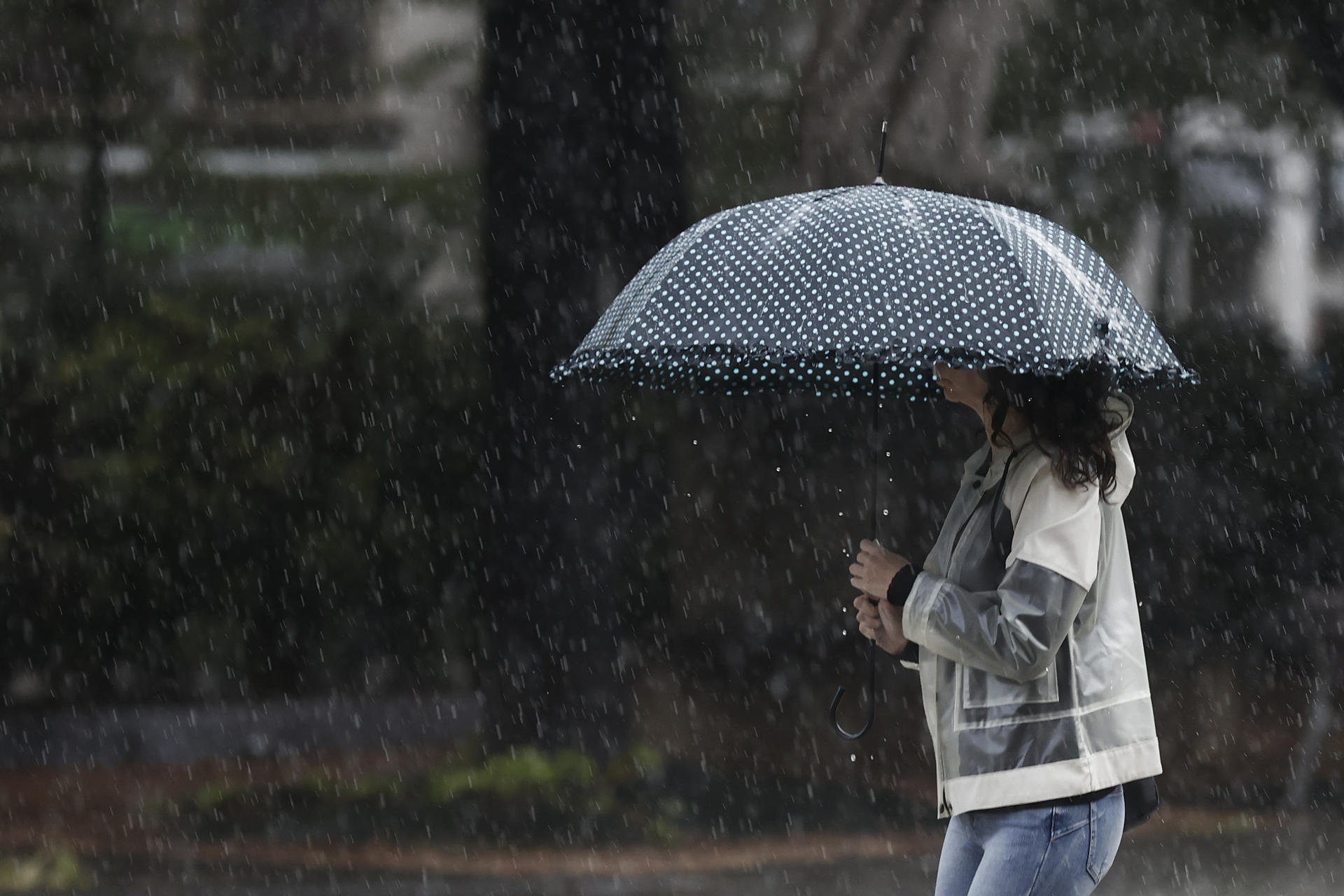 Una mujer se protege de la lluvia con un paraguas en una jornada donde el ambiente inestable, con chubascos localmente fuertes y de cierta intensidad continúa en la Comunidad Foral.  EFE/ Jesús Diges
