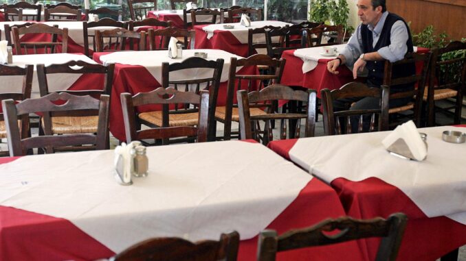 Imagen de archivo de un camarero que espera la llegada de clientes en un restaurante en Atenas, Grecia. EFE/Orestis Panagiotou
