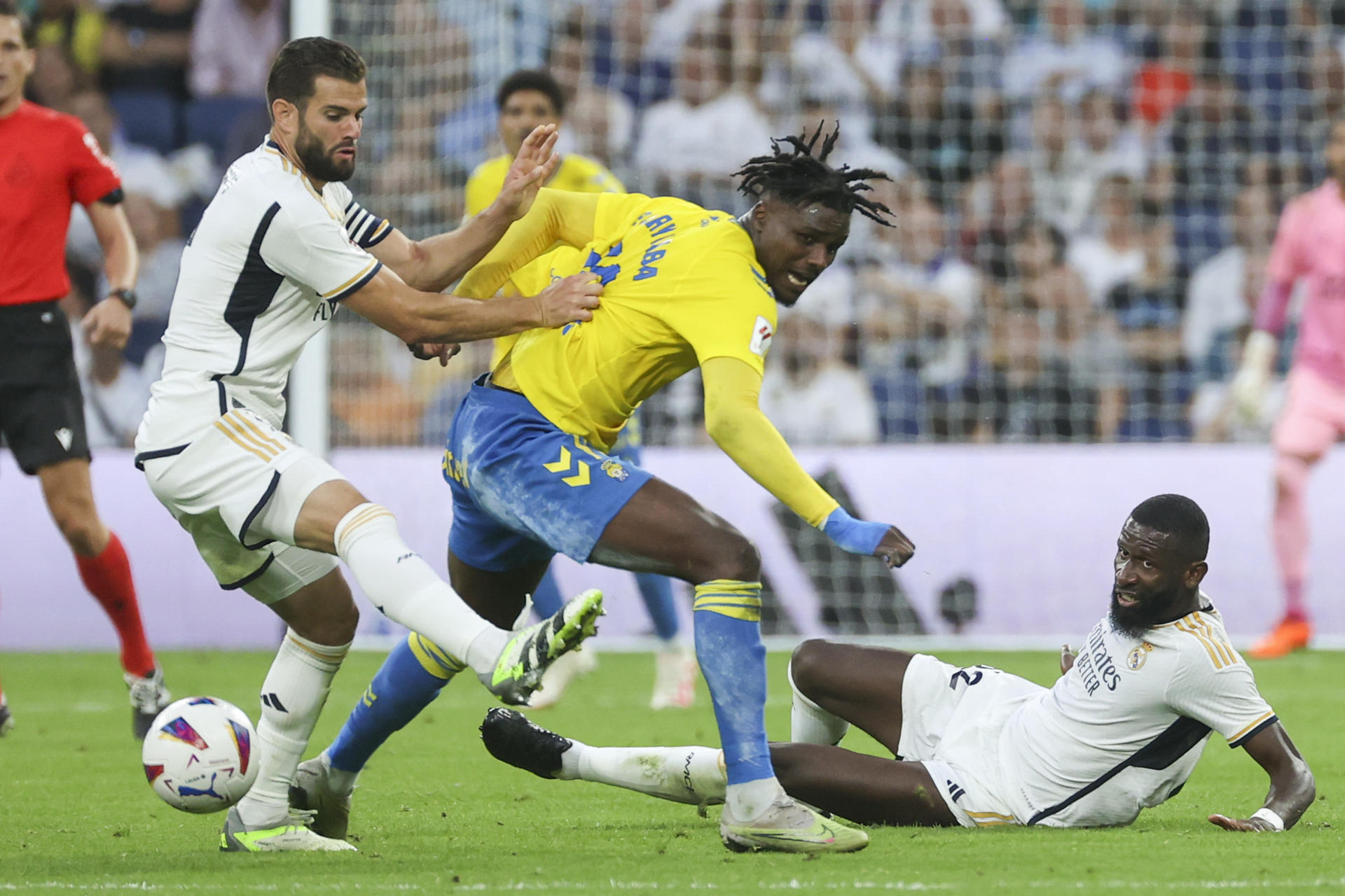 El delantero guineano de la UD Las Palmas Sory Kaba (c) rodeado de Antonio Rudiger (d) y Nacho Fernández, ambos del Real Madrid durante el encuentro de la jornada 7 de LaLiga EA Sports entre el Real Madrid y la UD Las Palmas en el Estadio Santiago Bernabéu, este miércoles en Madrid. EFE/Kiko Huesca
