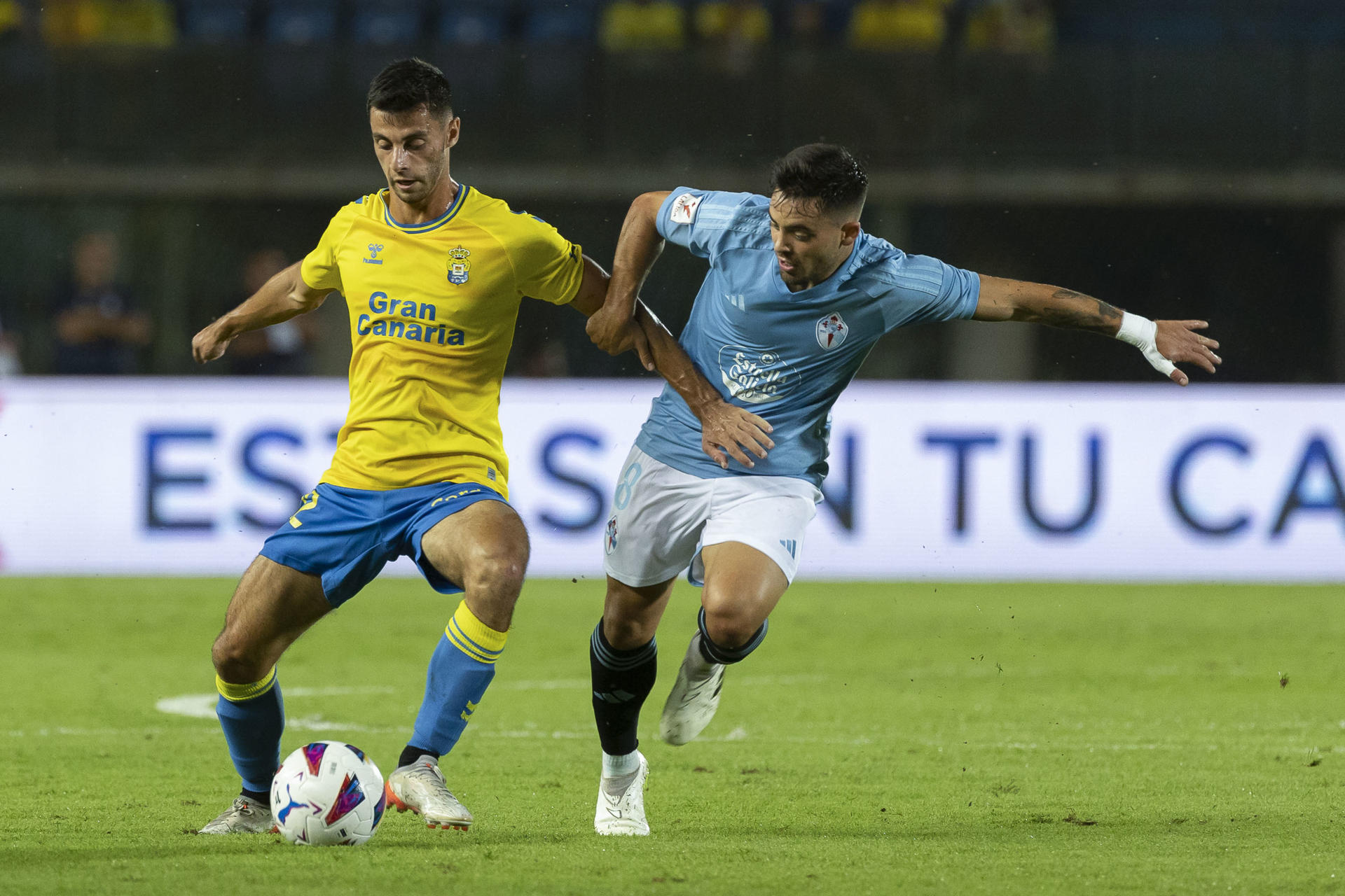 El centrocampista francés de Las Palmas Enzo Loiodice (i) pelea un balón con el centrocampista del Celta Fran Beltrán durante el partido de LaLiga que se disputa este lunes en el estadio de Gran Canaria. EFE/ Quique Curbelo
