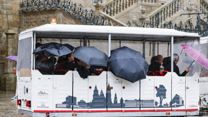 Turistas sorprendidos por el viento y la lluvia en la plaza del Obradoiro de Santiago de Compostela. EFE/Lavandeira jr
