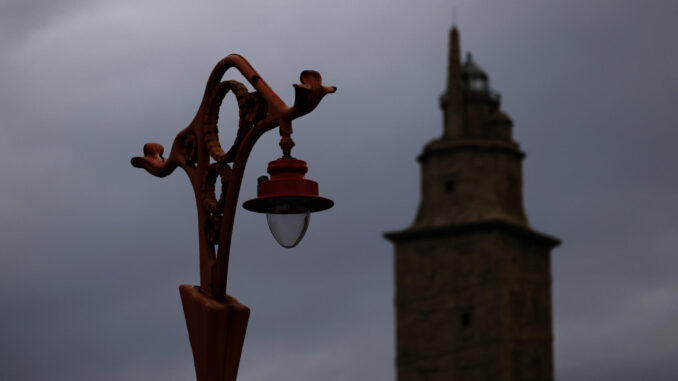 Una farola del paseo marítimo de A Coruña, con la Torre de Hércules en segundo plano, en una jornada de inestabilidad con borrascas, especialmente en el oeste peninsular, que vendrán acompañadas por fuertes vientos. EFE/Cabalar
