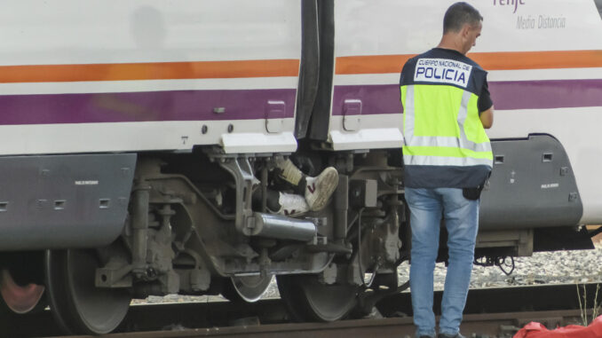 Un agente del Cuerpo Nacional de Policía junto al cuerpo de una persona que ha sido hallado este lunes entre dos vagones de un tren en la estación de Santa Justa de Sevilla, donde el pasado jueves desapareció el joven cordobés de 18 años Álvaro Prieto. EFE/ Raúl Caro