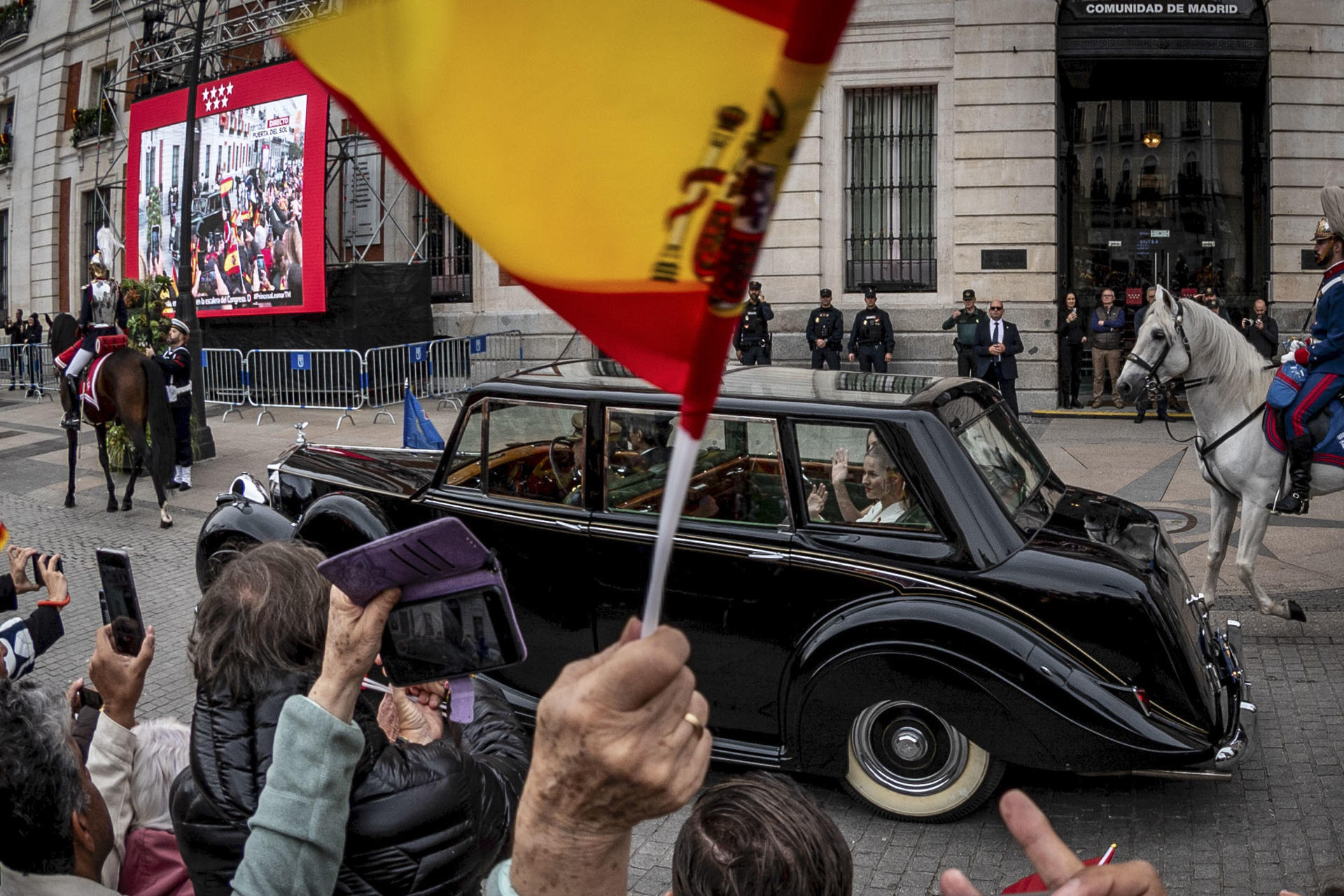 La princesa Leonor, acompañada por la infanta Sofía, a bordo del Rolls Royce Phamton IV y escoltadas por la Guardia Real Motorizada, saluda a los ciudadanos a su paso por la Real Casa de Correos, sede del Gobierno de la Comunidad de Madrid, en su trayecto hacia el Congreso de los Diputados, donde este martes tiene lugar la jura de la Constitución de la Princesa de Asturias por su mayoría de edad ante las Cortes Generales, en una solemne sesión conjunta de las dos cámaras legislativas que se celebra en el hemiciclo de la Cámara Baja. EFE/ Fernando Villar
