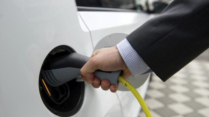 Un hombre conecta el cargador al coche eléctrico, en una fotografía de archivo. EFE/Sebastian kahnert
