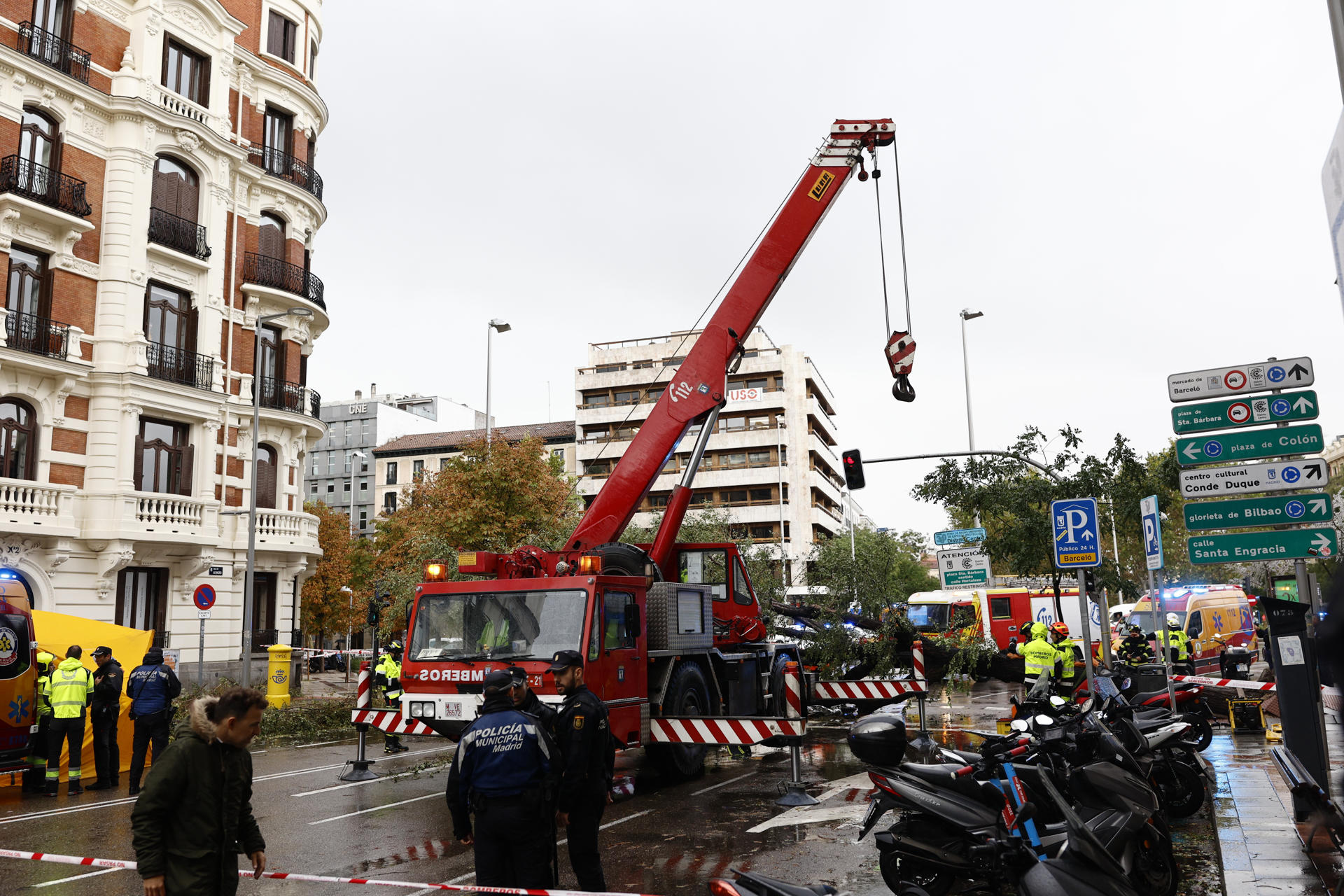 Efectivos del cuerpo de bomberos permanecen en el número 1 de la calle Almagro de Madrid, donde este jueves una mujer de 23 años ha fallecido tras caerle un árbol encima a causa de las fuertes rachas de viento. EFE/ Rodrigo Jimenez
