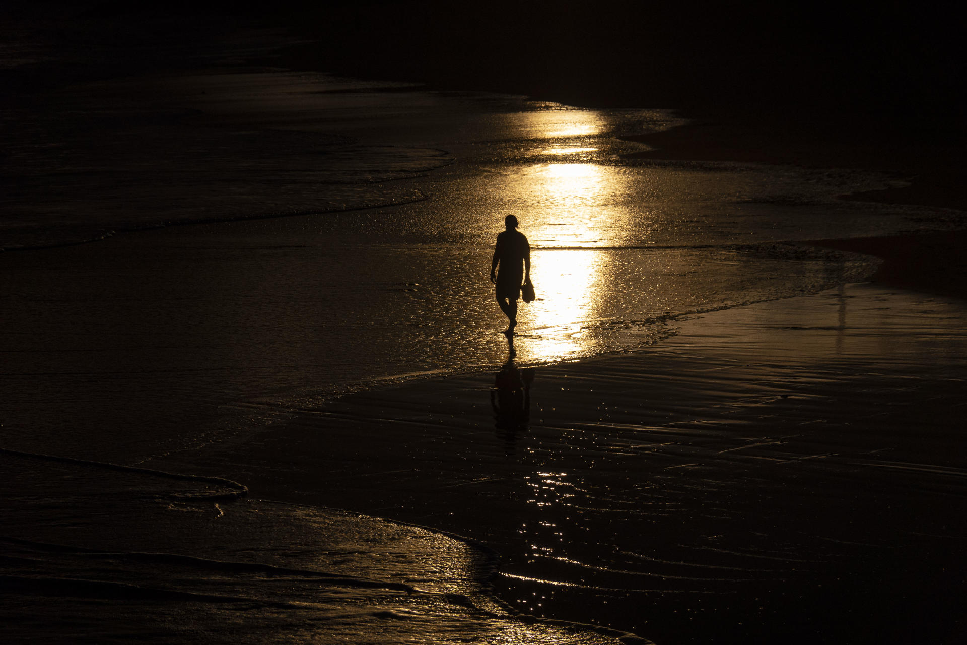 Una persona pasea por la playa de Ondarreta durante el amanecer, este martes, en San Sebastián. EFE/Javier Etxezarreta
