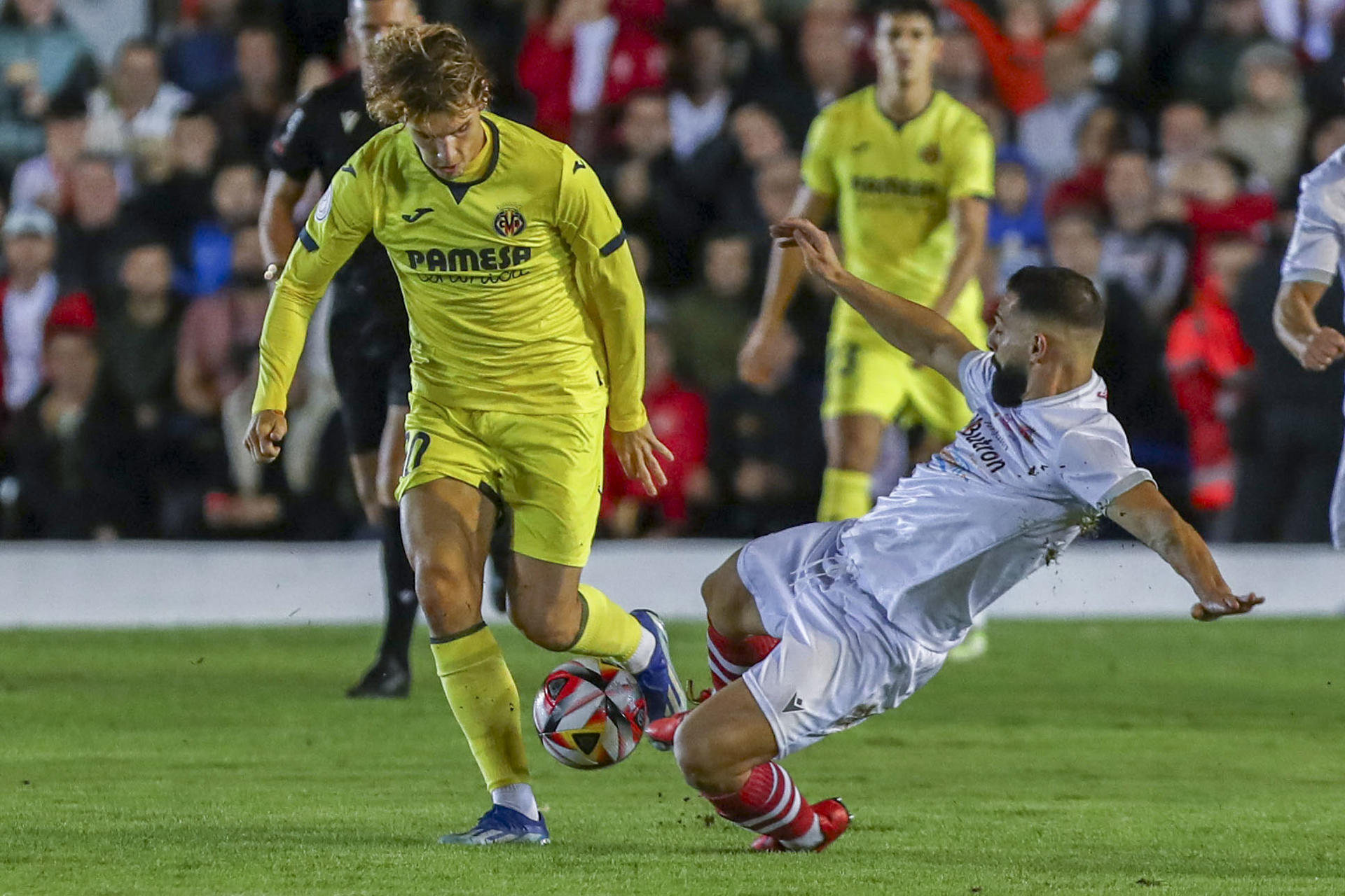 CHICLANA DE LA FRONTERA (CÁDIZ), 02/11/2023.- El centrocampista del Chiclana, Juanito (d), disputa el balón con Carlos Romero (i), jugador del Villarreal, durante el partido de primera ronda de Copa del Rey entre Chiclana CF y Villarreal CF, este jueves en el Campo Municipal de Chiclana, en Chiclana de la Frontera. EFE/Román Ríos
