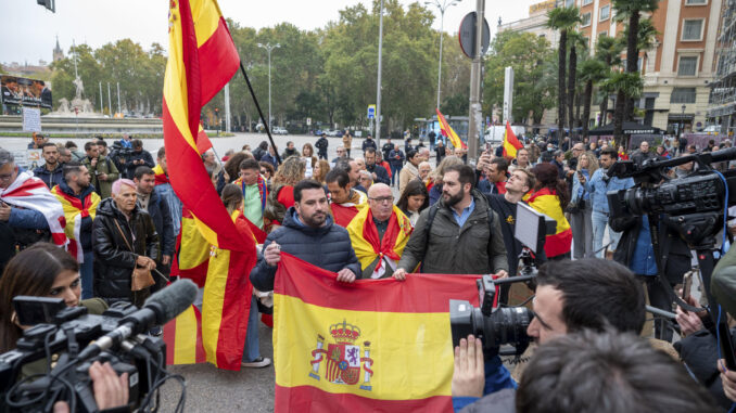 Varias personas con banderas de España protestan en las inmediaciones del Congreso de los Diputados donde este miércoles se celebra la primera jornada del debate de investidura del líder del PSOE, Pedro Sánchez, que expondrá su nuevo programa de Gobierno y pedirá la confianza a la Cámara para revalidar su mandato en la Moncloa. EFE/ Fernando Villar
