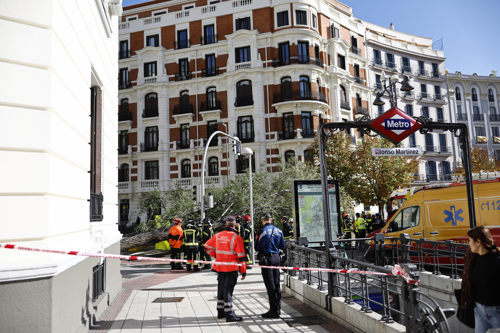 Efectivos de los servicios médicos y de la policía permanecen en el número 1 de la calle Almagro de Madrid, donde este jueves una mujer joven ha fallecido tras caerle un árbol encima a causa de las fuertes rachas de viento. EFE/ Rodrigo Jimenez
