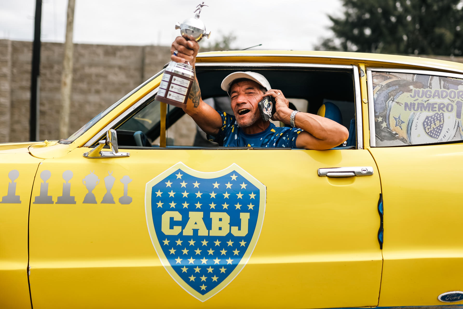 Un aficionado del Boca Juniors posa con una copa durante el acompañamiento que un grupo de hinchas hace al equipo en el camino hacia el aeropuerto hoy, en Buenos Aires (Argentina). EFE/Juan Ignacio Roncoroni
