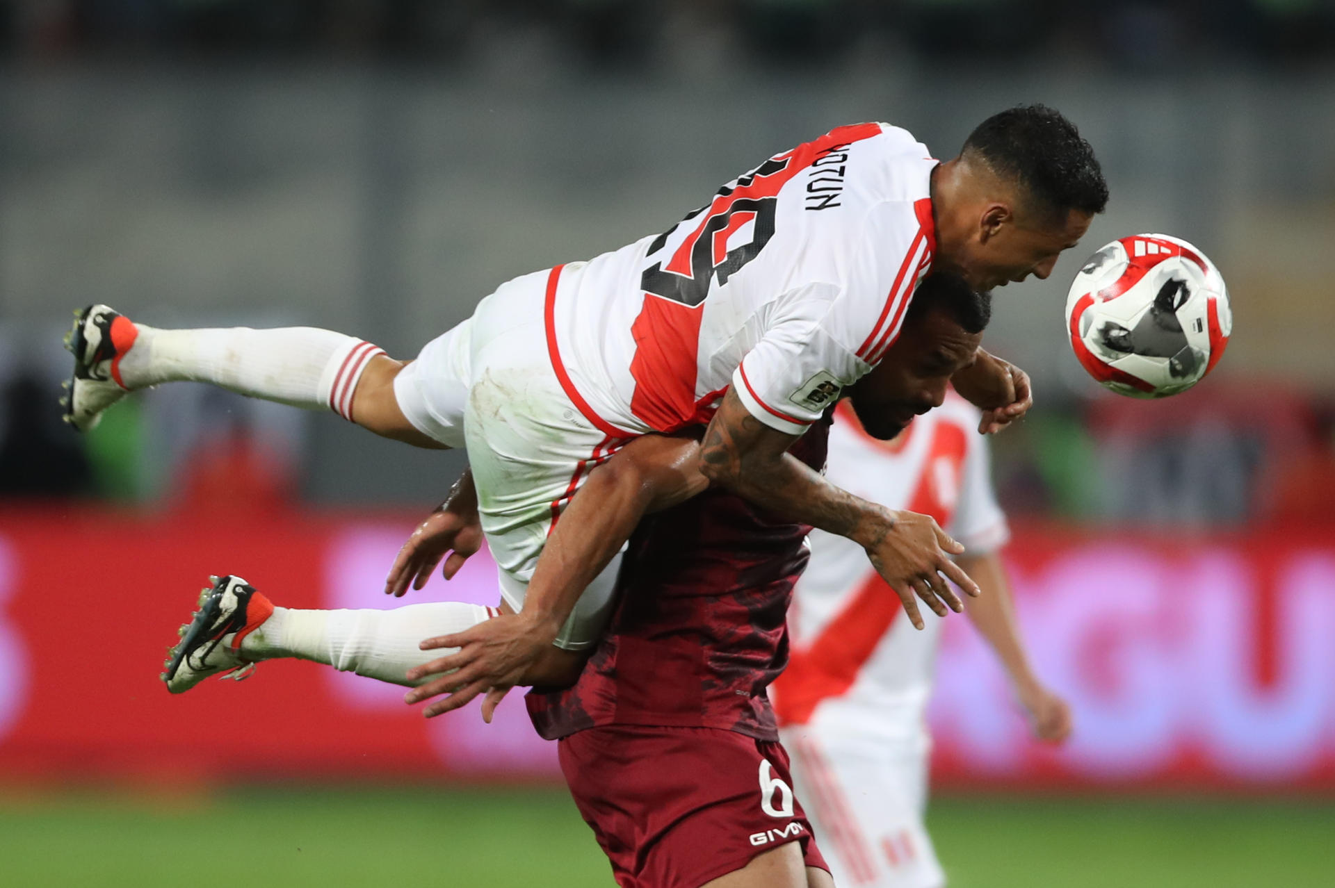 Yoshimar Yotún (arriba) de Perú disputa el balón con Yangel Harrera de Venezuela este 21 de noviembre de 2023, en un partido de las eliminatorias para la Copa Mundo de Fútbol de 2026. EFE/ Paolo Aguilar
