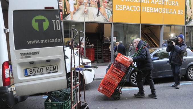 Uno de lo comerciantes del Mercado de Torrijos se dirige al camión para cargar género fresco ante un cartel que anuncia la apertura de una nueva iniciativa comercial en el espacio del mercado este miércoles en Madrid. EFE/ Fernando Alvarado
