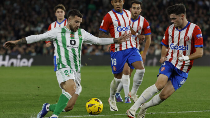 El defensa del Real Betis Aitor Ruibal (i) lucha con Sávio Moreira de Oliveira (c) y Miguel Gutiérrez, ambos del Girona FC, durante el encuentro correspondiente a la jornada 18 de LaLiga que Real Betis y Girona FC jugaronen el estadio Benito Villamarín, en Sevilla. EFE/ Julio Muñoz
