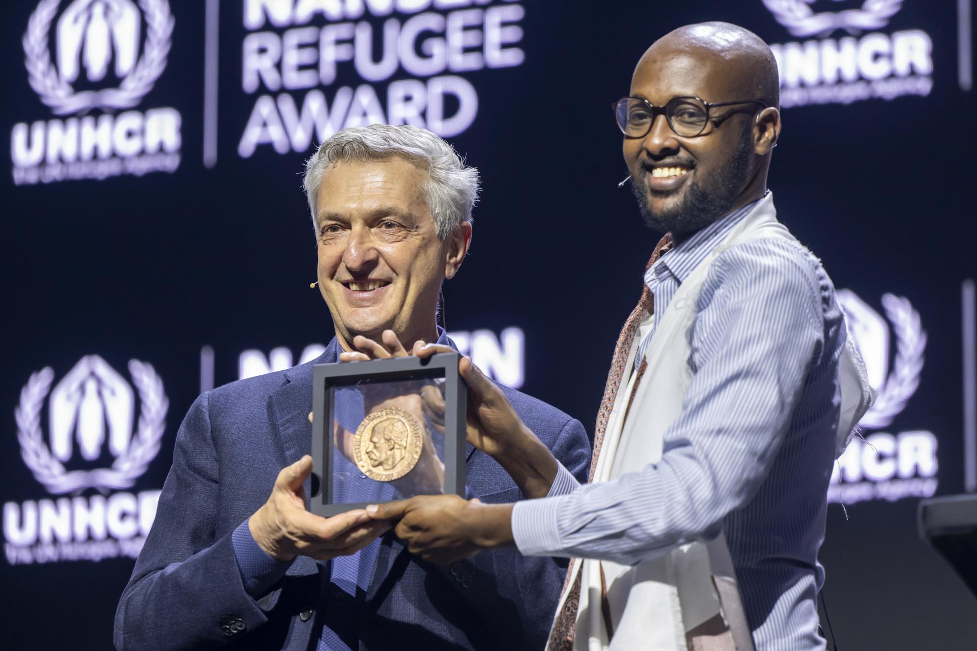 El antiguo refugiado somalí Abdullahi Mire recibe un premio junto a Filippo Grandi, alto comisionado de la ONU para los refugiados, en Ginebra. EFE/EPA/MARTIAL TREZZINI / POOL
