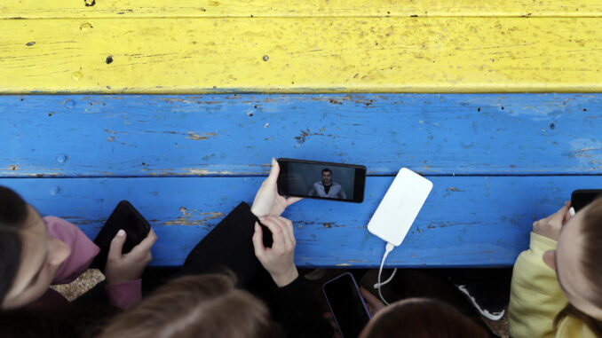 Cuatro estudiantes miran las noticias en un teléfono móvil. EFE/Kai Försterling
