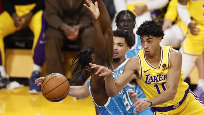 El jugador de los Angeles Lakers Max Christie (d) pasa el balón a un compañero de equipo mientras está custodiado por Nathan Mensah (i), de los Charlotte Hornets, durante el partido de baloncesto de la NBA entre Los Angeles Lakers y Charlotte Hornets en Los Ángeles. EFE/EPA/CAROLINE BREHMAN
