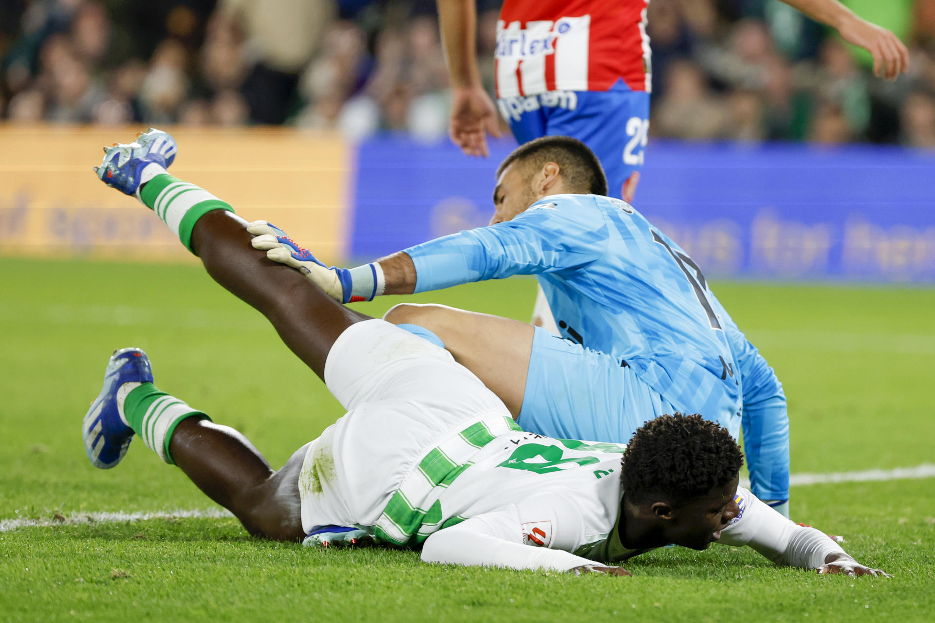 El delantero senegalés del Real Betis Assano Diao (primer plano) disputa una posesión con el guardameta del Girona FC Paulo Gazzaniga durante un encuentro correspondiente a la jornada 18 de LaLiga en el estadio Benito Villamarín de Sevilla. EFE/ Julio Muñoz
