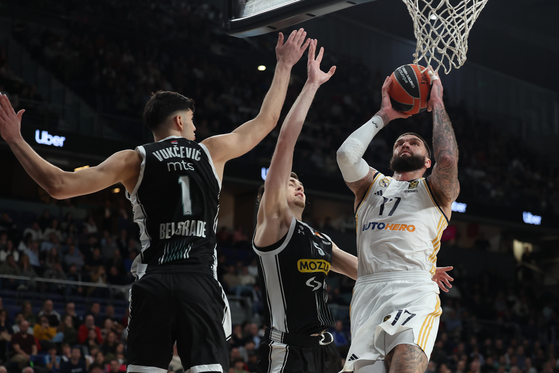 El pívot francés del Real Madrid Vincent Poirier (d) entra a canasta defendido por Balša Koprivica (c) y Tristan Vukcevic (i), ambos del Partizán, durante el partido de la jornada 16 de la EuroLiga que Real Madrid y Partizán de Belgrado disputaron en el WiZink Center, en Madrid. EFE/Kiko Huesca
