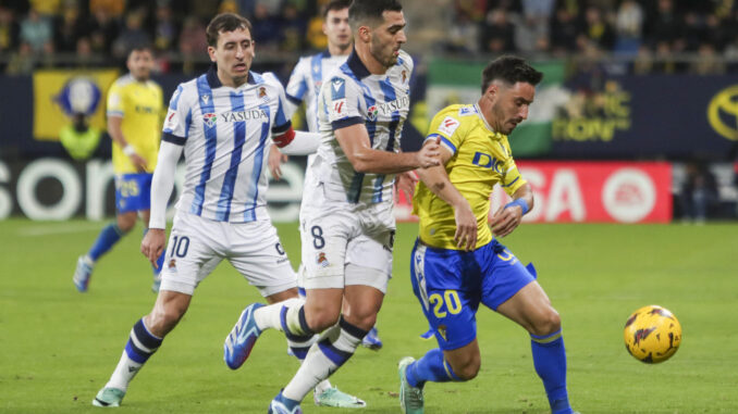 El centrocampista del Real Sociedad Mikel Merino (2d) lucha por el balón con el defensa del Cádiz CF Isaac Carcelén "Iza" (d) durante el partido de LaLiga en el Estadio Nuevo Mirandilla. EFE/Román Ríos.
