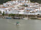 Vista de la localidad portuguesa de Alcoutim con la barca de la empresa ‘Fun River’, que todos los días del año hace el recorrido entre Alcoutim (Portugal) y Sanlúcar de Guadiana (Huelva) -al fondo-, un servicio que sobrevive con el paso de los años a pesar de que ya hay cuatro pasos por carretera para cruzar entre Andalucía, a través de la provincia onubense, y Portugal. Ninguno de los 400 habitantes de Sanlúcar de Guadiana, en Huelva, recuerda desde cuándo hay una barca que cruza el río para llegar a Alcoutim, su vecina portuguesa al otro lado del río, pero, en la era de la tecnología más avanzada, este servicio se mantiene igual que décadas e incluso siglos atrás, con un barquero que trabaja de sol a sol.-EFE/ Fermín Cabanillas