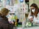 Una farmacéutica atiende a una cliente, ambas con mascarilla, en una farmacia esta semana. EFE/Nacho Gallego