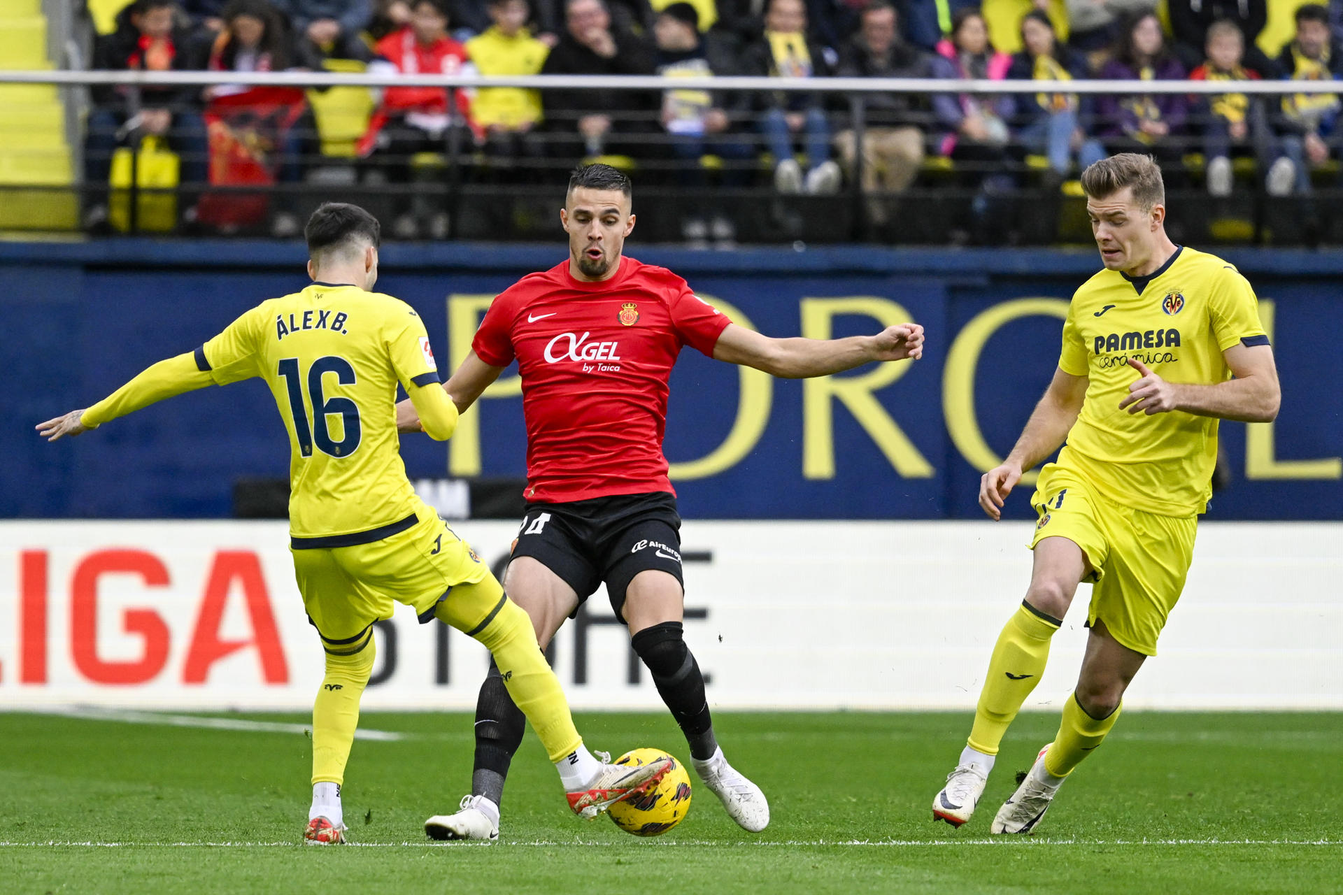 El defensa eslovaco del Mallorca Martin Valjent (c) y el centrocampista del Villarreal Álex Baena luchan por el balón durante el partido de la jornada 21 de Ligaen el estadio La Cerámica de Villarreal. EFE/ Andreu Esteban
