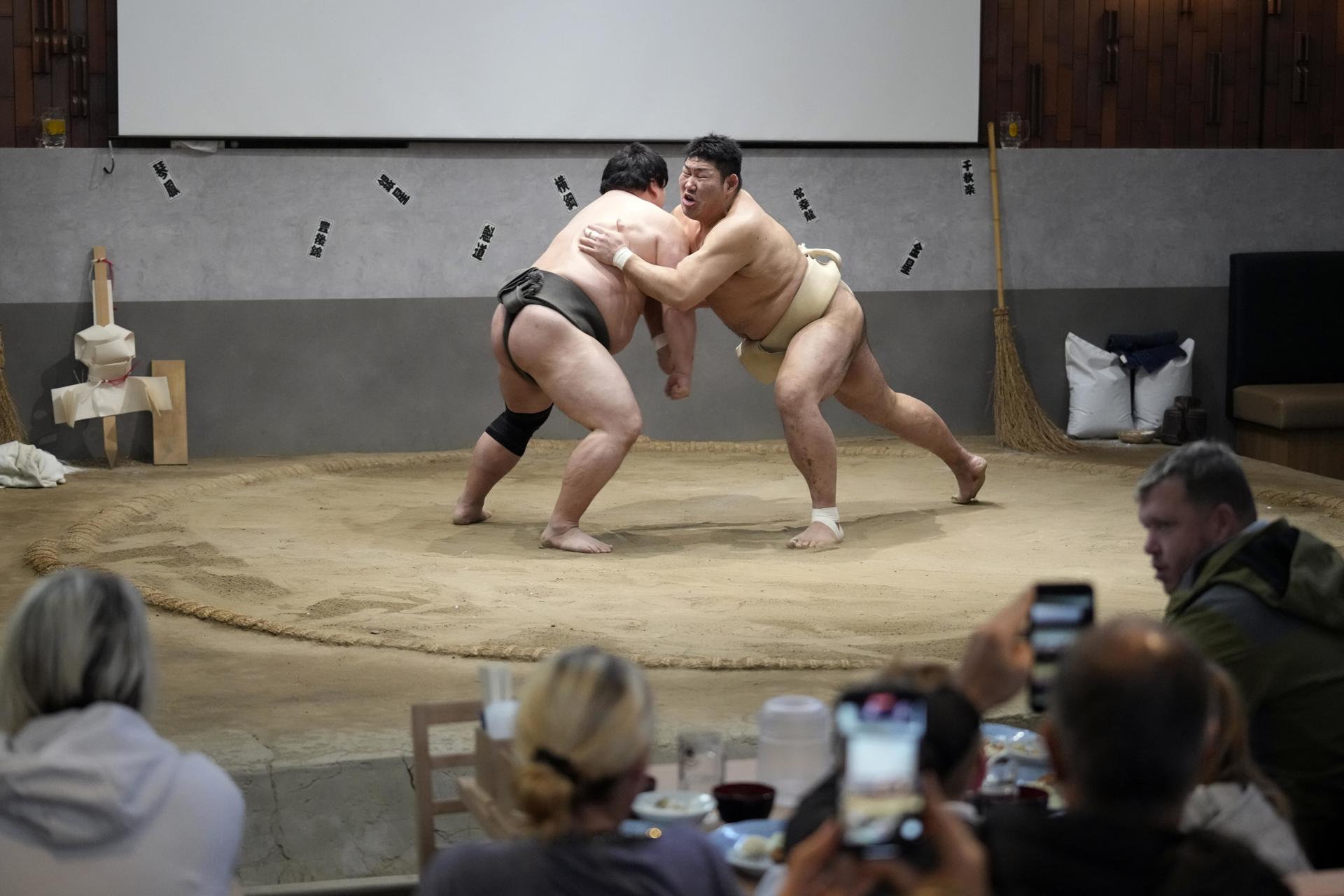 Los ex luchadores de sumo Matsunoumi (izq.) y Jokoryu (dcha.) actúan en un ring de sumo ante turistas extranjeros durante un almuerzo con espectáculo de sumo en el restaurante Yokozuna Tonkatsu Dosukoi Tanaka, en Tokio. EFE/EPA/FRANCK ROBICHON
