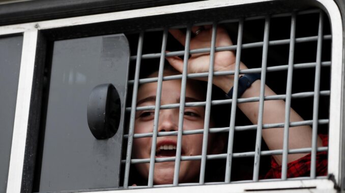 Foto archivo. Una mujer detenida por la Guardia Nacional rusa observa desde la ventana de un vehículo durante una manifestación en apoyo a periodista ruso detenido.EFE/ Yuri Kochetkov
