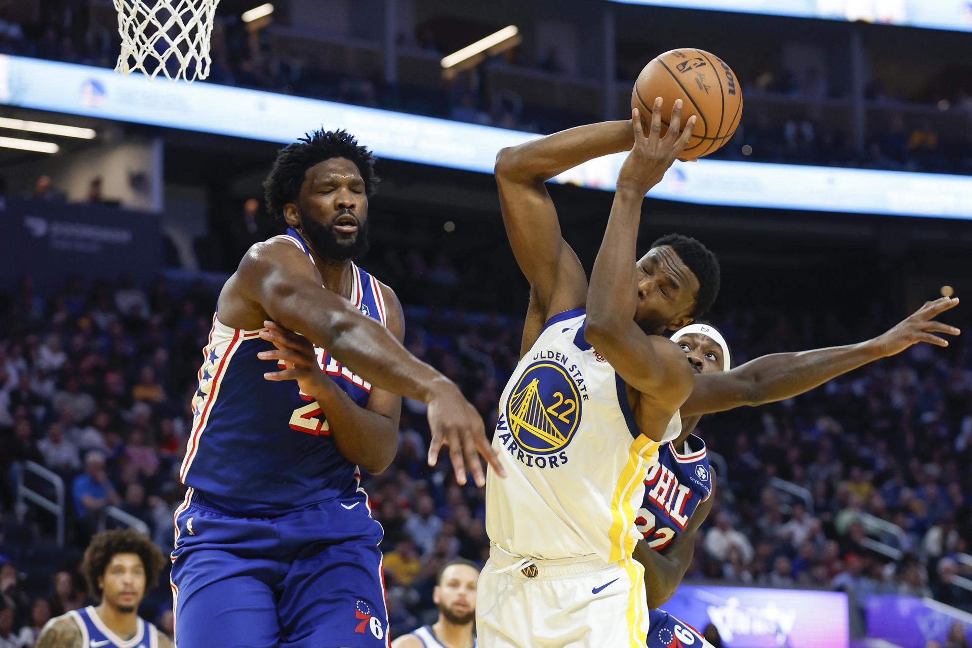 El jugador de los Golden State Warriors Andrew Wiggins (c) se dirige a canasta mientras saca una falta del jugador de Philadelphia 76ers Joel Embiid (i) durante la primera mitad del partido de la NBA entre los Golden State Warriors y Philadelphia 76ers en San Francisco, California. EFE/EPA/JOHN G. MABANGLO
