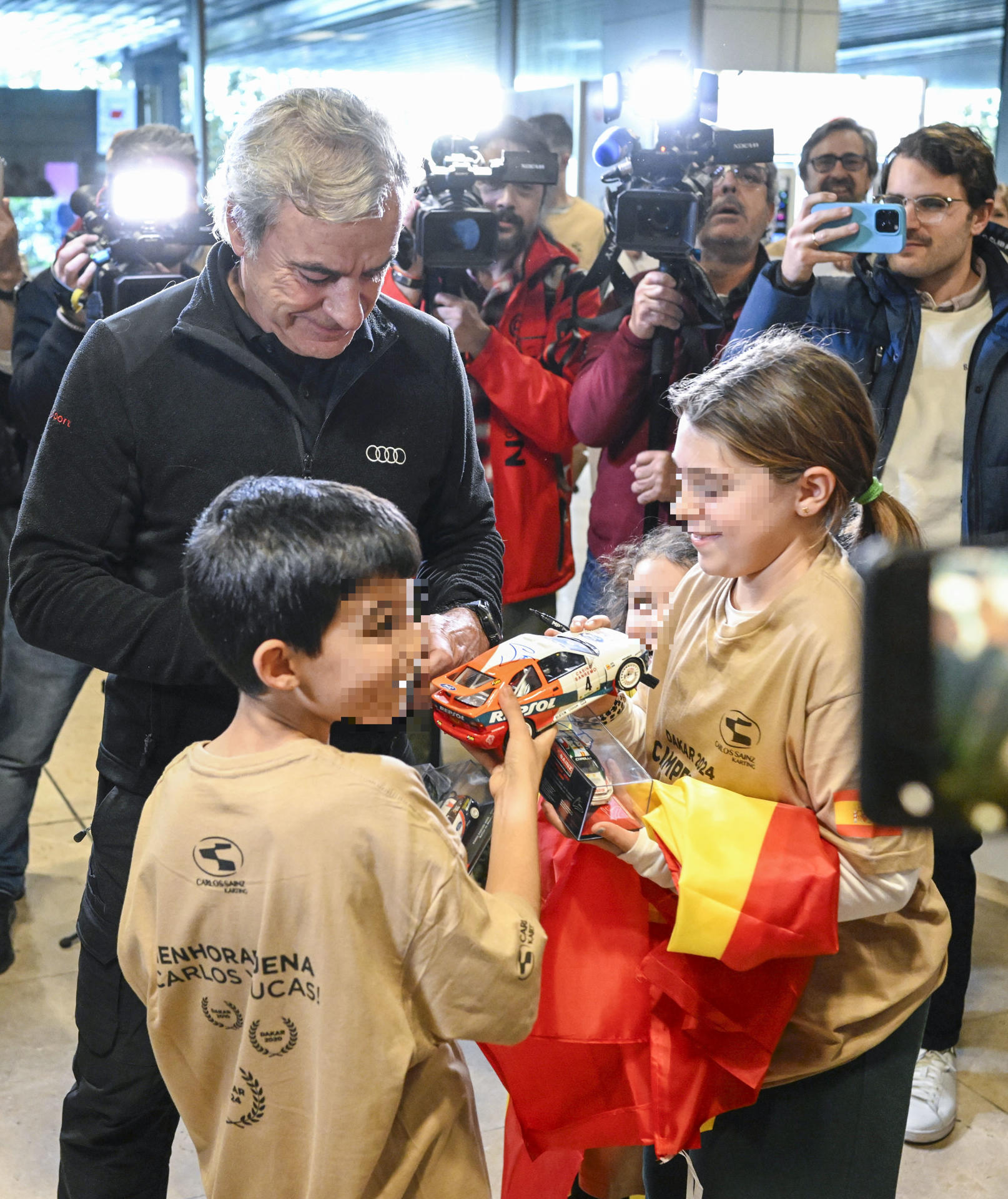 El piloto español Carlos Sainz (Audi) firma autógrafos a su llegada este sábado al aeropuerto Adolfo Suárez-Madrid Barajas. Los españoles Carlos Sainz (Audi) y Cristina Gutiérrez (Red Bull) entraron en la historia del Dakar; el madrileño por conseguir su cuarto Touareg y la burgalesa por ser la segunda mujer en ganar la prueba, tras un rally marcado por la muerte del catalán Carles Falcón. EFE/ Víctor Lerena
