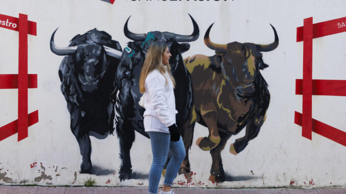 Una mujer pasa delante de un mural durante los "Encierros Blancos" en San Sebastián de los Reyes, Madrid, este sábado. EFE/Sergio Pérez
