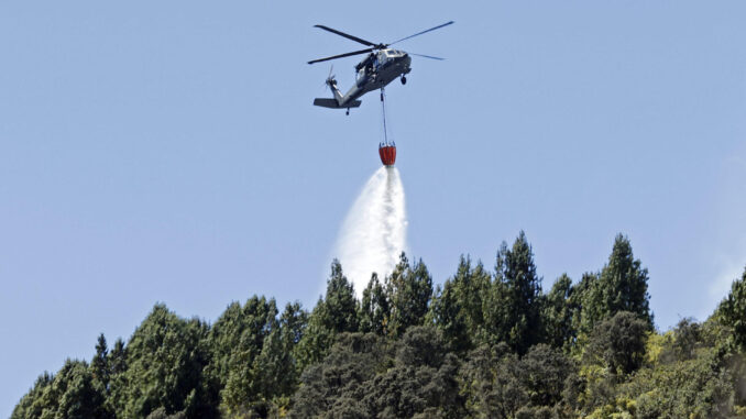 Fotografía de un helicóptero mientras hace una descarga de agua en la zona de un incendio forestal hoy, en el cerro El Cable, en Bogotá (Colombia). EFE/Mauricio Dueñas Castañeda
