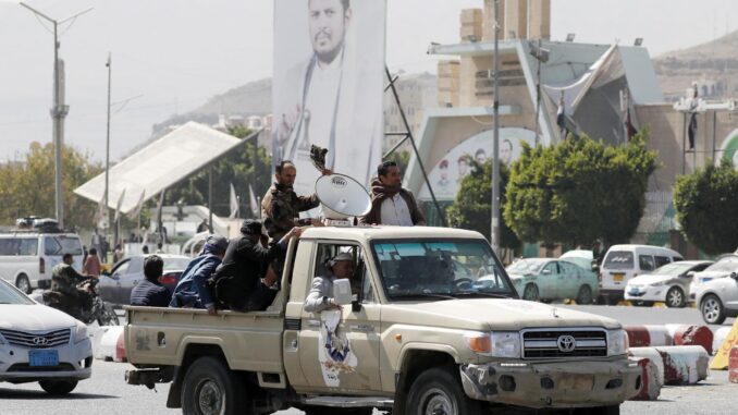 Simpatizantes hutíes viajan en un vehículo pasando junto a una pancarta que representa al máximo líder hutí, Abdul-Malik al-Houthi, en una calle de Saná, Yemen, en una fotografía de archivo. EFE/EPA/Yahya Arhab
