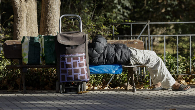 Una persona sin hogar descansa junto a sus pertenencias en un banco público. EFE/Ana Escobar