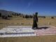 Un integrante de una tribu leal a los hutíes camina encima de las banderas de Israel y Estados Unidos durante un encuentro para combatientes recientemente reclutados el 22 de enero en las afueras de Saná. EFE/YAHYA ARHAB