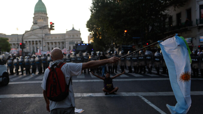 Un manifestante ondea una bandera de Argentina frente a policías antidisturbios formados durante una protesta contra el proyecto de la 'Ley Ómnibus' a las afueras del Congreso argentino ayer, en Buenos Aires (Argentina). EFE/ Juan Ignacio Roncoroni
