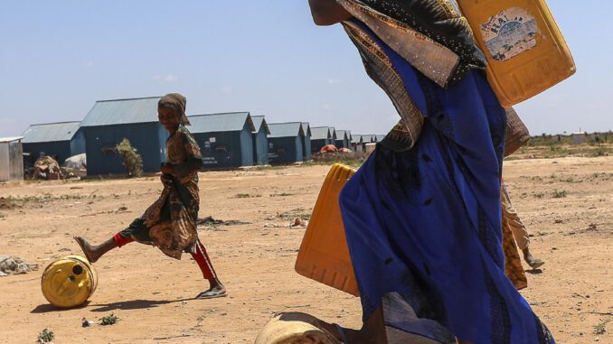 Una mujer y sus hijos llevan bidones de agua en el campamento de desplazados de Ladan, a las afueras de la localidad somalí de Dollow. EFE/EPA/Daniel Irungu
