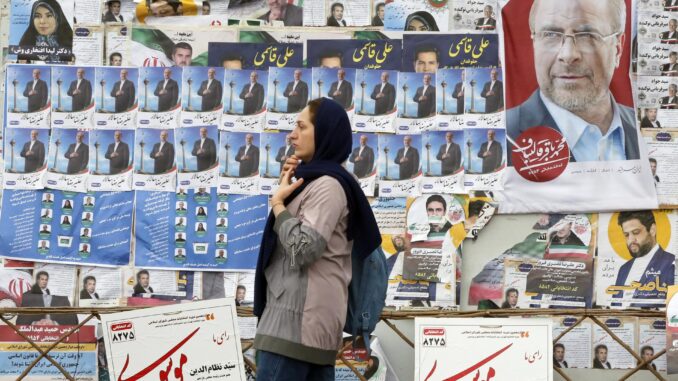 Una mujer iraní pasa por delante de carteles electorales de candidatos a las elecciones parlamentarias que se celebran en Irán el 1 de marzo de 2024. EFE/EPA/ABEDIN TAHERKENAREH
