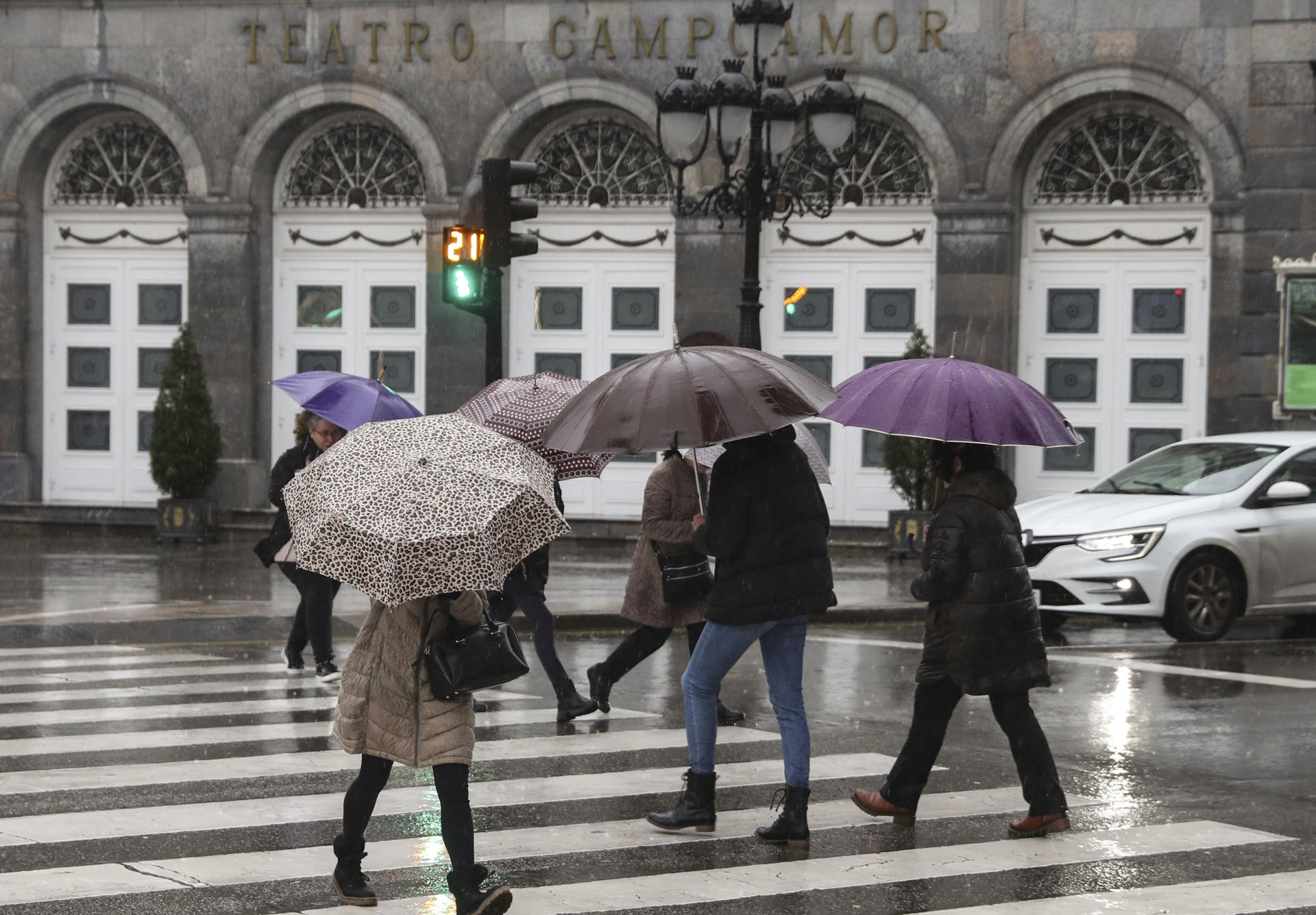 Varias personas se protegen de la lluvia este lunes en una calle del centro de Oviedo. EFE/ J.L.Cereijido
