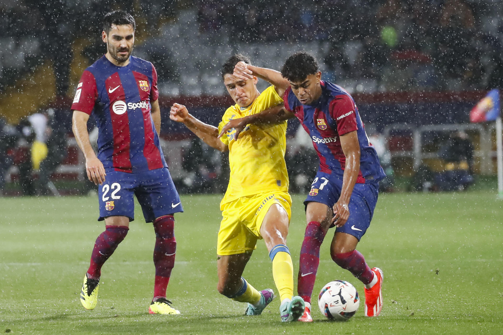 El delantero del FC Barcelona Lamine Yamal (d) lucha con Sergi Cardona (c), de la UD Las Palmas, durante el partido de la jornada 30 de LaLiga en el estadio olímpico Lluís Companys. EFE/ Marta Pérez
