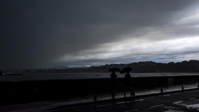 Dos hombres caminan bajo la lluvia este lunes en San Sebastián. EFE/Javier Etxezarreta
