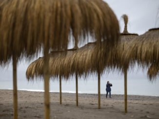 Una persona camina por la playa de Los Álamos en Torremolinos, bajo la lluvia que está cayendo en la provincia de Málaga este domingo. EFE/Daniel Pérez